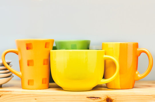 colored cups on the wooden shelf