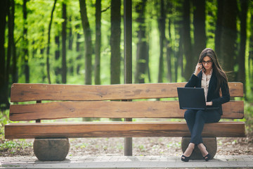 woman works behind laptop in the park