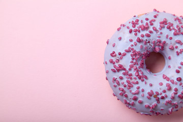 Close up view of sweet glazed raspbrery donut on pink background with text space on the left