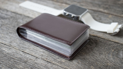 smart watch and business card holder on wooden background. Trendy new technology that let you always stay connected to internet and news.