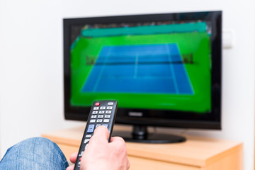 Man watching a tennis match on TV