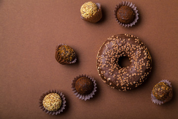 Chocolate donuts with chocolate truffles on brown background. Monochromatic concept.