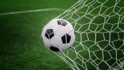 Naklejka na ściany i meble Soccer ball on goal with net and green background