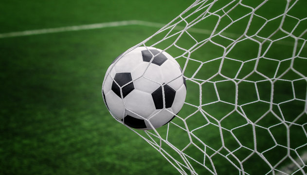 Soccer ball on goal with net and green background