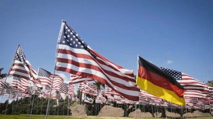slow motion waving german flag in between american flags. diplomatic concept - Powered by Adobe