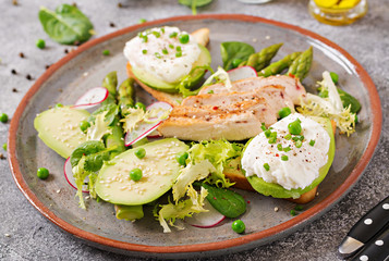 Healthy breakfast. Eggs poached on toast with avocado, asparagus and chicken fillet on grill.