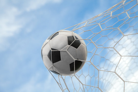 Soccer ball on goal with net and sky background