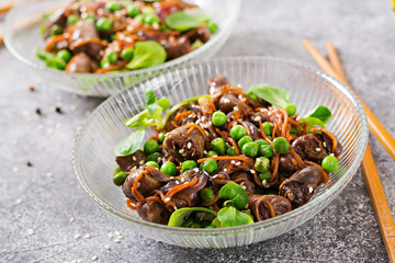 Chicken hearts with carrots, onions and green peas in Asian style.