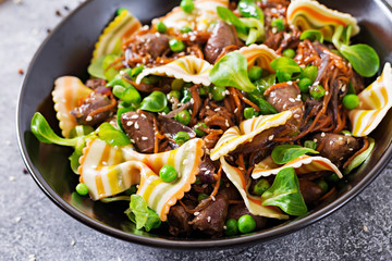 Chicken hearts with carrots in sweet and sour sauce with farfalle pasta. Healthy salad