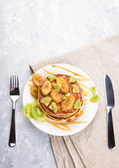 Homemade breakfast on a marble grey table. Stack of pancakes with a grilled bananas and a caramel, kiwi slices. Healthy breakfast concept, flat lay, top view