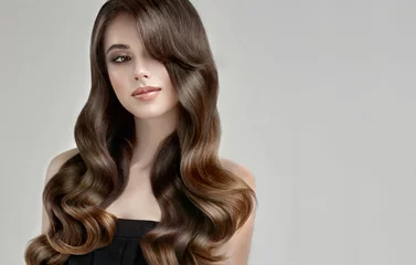 Photo sur Aluminium Salon de coiffure Fille brune aux cheveux bouclés longs, sains et brillants. Belle femme modèle avec une coiffure ondulée. Soins et beauté