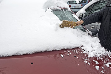Driver cleans the snow from the car