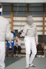 Two young fighters in protective mask fighting at the fencing competition