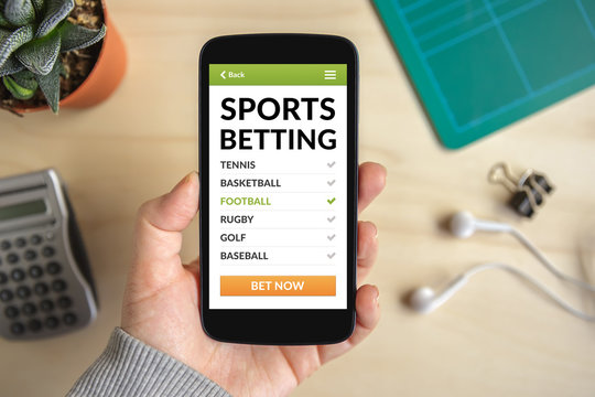 Hand holding smart phone with sports betting concept on screen. All screen content is designed by me. Flat lay