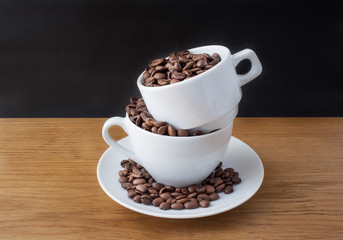 Coffee beans in the cup on wooden table with black background