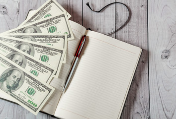 Notepad, pen and money on a light wooden background