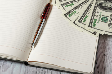 Notepad, pen and money on a light wooden background