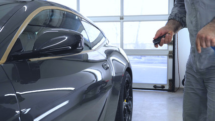 The specialist checks the car, shines a flashlight, after polishing, washing machines.
