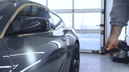 The specialist checks the car, shines a flashlight, after polishing, washing machines.