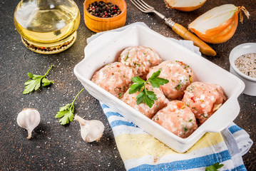 Raw homemade chicken or turkey meatballs in baking dish dark rusty background. Copy space