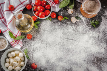 Homemade pasta pizza italian food ingredient on dark rusty table with flour, olive oil, basil, tomatoes and kitchen accessories top view