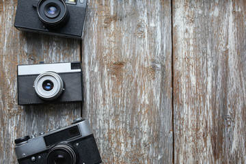 Old photo cameras on old wooden texture. Vintage film cameras on background. Retro and antique photography.