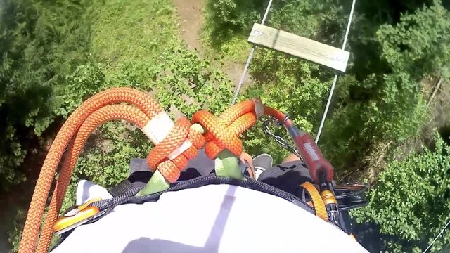 Personal perspective of climbing in adventure rope park, climbing trees in forest in summer - video HD