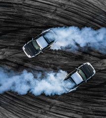 Top view two drifting car on asphalt street road texture and background, Aerial view professional adrenaline driver acceleration drifting car on race track, Automobile and automotive concept. © Kalyakan