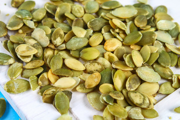 Full bowl of pumpkin seeds close up on a wooden table.