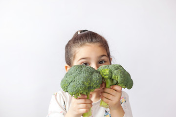 Happy little girl eating fresh vegetables. A portrait of cute child girl on a white background....