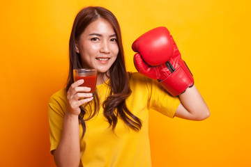 Young Asian woman with tomato juice and boxing glove in yellow dress