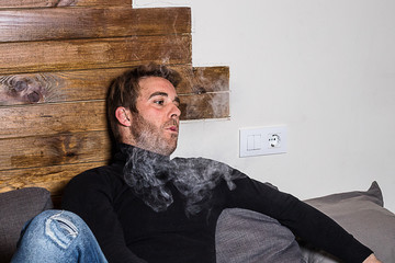 Normal guy smoking on the couch at home.