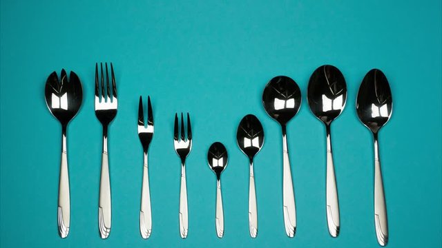 Forks and spoons from small to large in one row on blue background. 