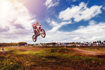 Racer on dirtbike motorcycle jumps and takes off over the track, in background opponent is catching...