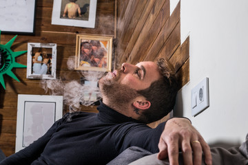 Normal guy smoking on the couch at home.