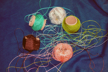 Threads for knitting on a blue background. Handmade concept. Crochet hooks and multi-colored yarn look bright.