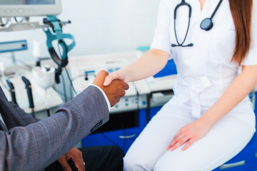 A beautiful female doctor holds the Asian patient's hand for encouragement and sympathy and touching her hand. The concept of partnership, trust and medical ethics. Bad news and support.