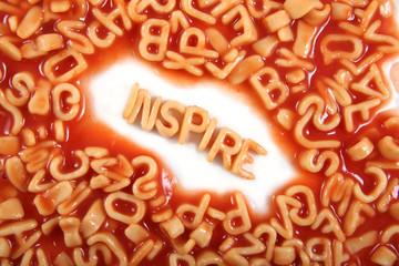 Inspire written in spaghetti pasta letters surrounded with jumbled letters.