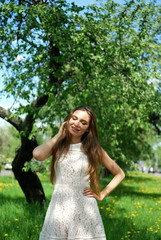 Beautiful smiling brunette girl standing in the alley in the summer background.