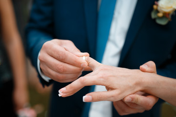 Wedding ceremony with bride and groom putting golden rings on each other fingers - 198323655