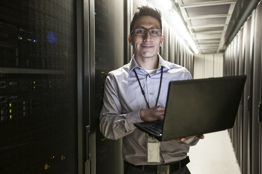 Hispanic man technician doing diagnostic tests on computer servers in a large server farm.