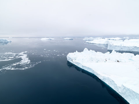 Arctic Icebergs at Greenland in the arctic sea. You can easily see that iceberg is over the water surface  and below the water surface. Sometimes unbelievable that 90%25 of an iceberg is under water.