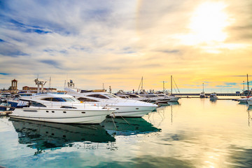 Luxury yachts at sunset. Marine dock of modern motor and sailing boats in sunshine, blue water sea,...