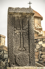 The darkened seventh century stone cross  at the entrance of the Church of Karmravor in the city of Ashtarak
