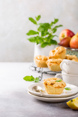 Homemade mini apple pies on white plates decorated with mint leaves on light concrete background. Healthy food concept with copy space.
