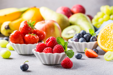 Fresh assorted fruits and berries on light gray background. Colorful clean and healthy eating. Detox food.