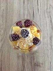 A glass of healthy and colorful breakfast with fruits blackberry pineapple yoghurt oatmeal
