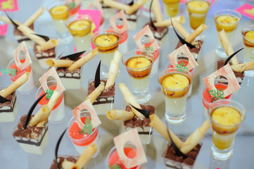 Fototapeta na wymiar Cream and berry desserts on the table of the restaurant buffet in glass cups are displayed in a row, toned image