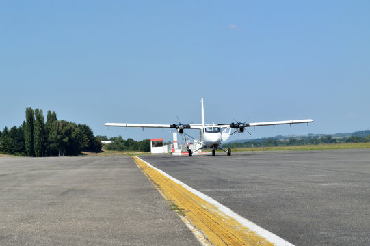 A twin plane waiting on an airport runway.