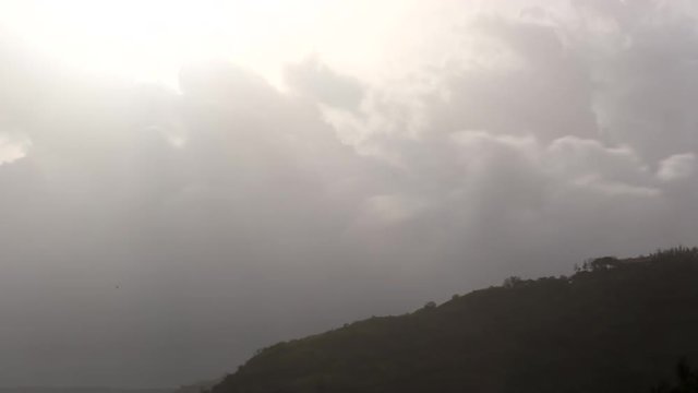 A stupendous time lapse of clouds passing west over a hill.